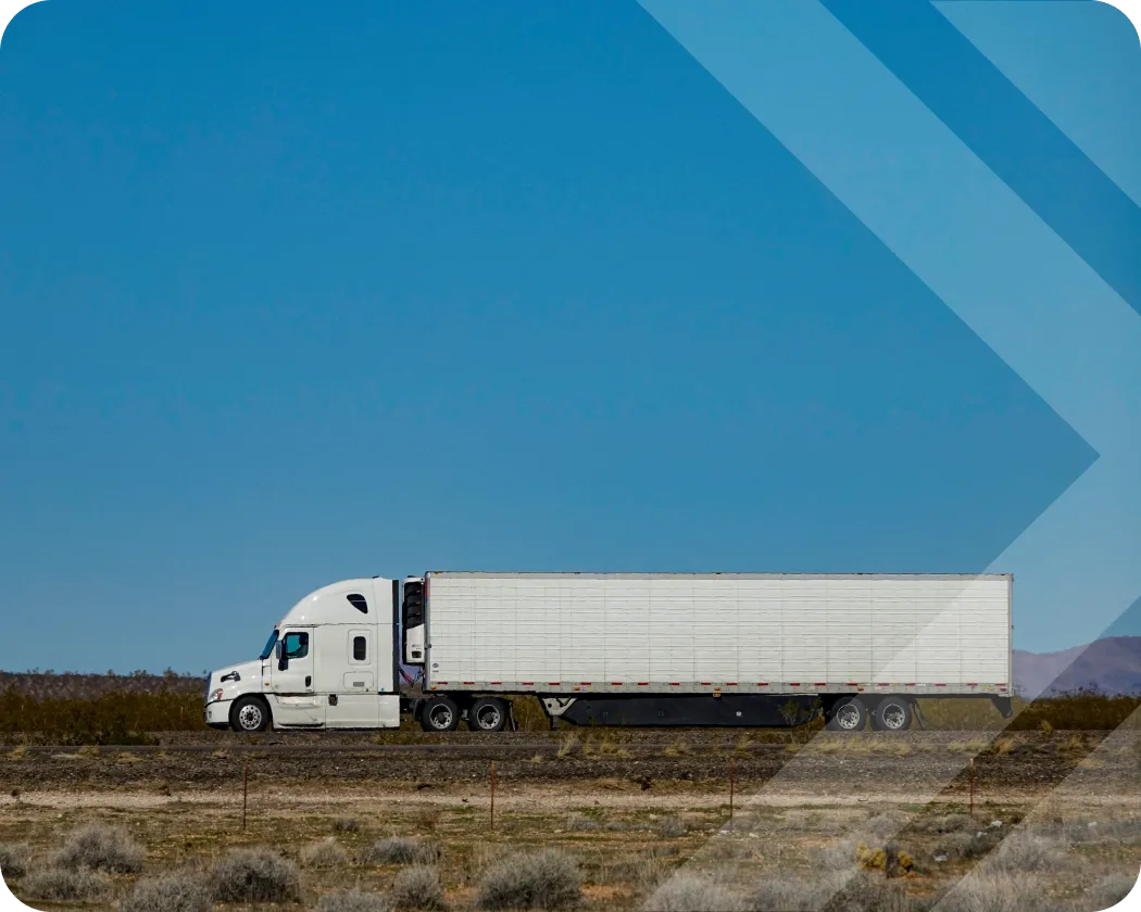 A semitruck driving on an open road with a blue sky.