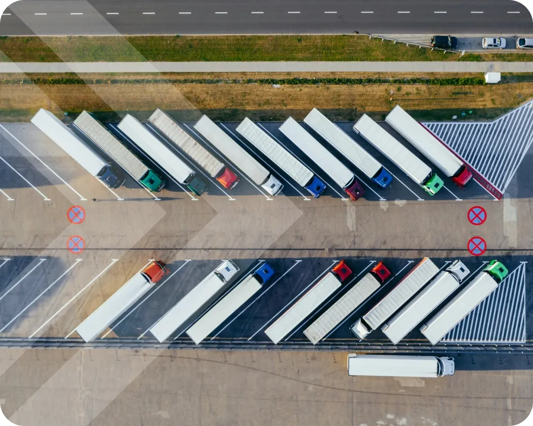 An overhead view of many semi-trucks lined up in parking spots.